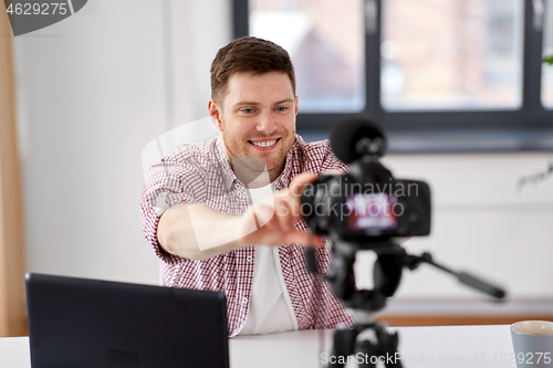 Image of male video blogger adjusting camera at home office