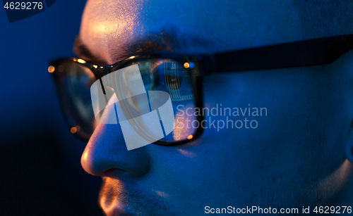 Image of close up of hacker in glasses looking at screen