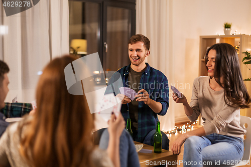 Image of friends playing cards and drinking beer at home