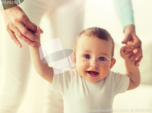 Image of happy baby learning to walk with mother help