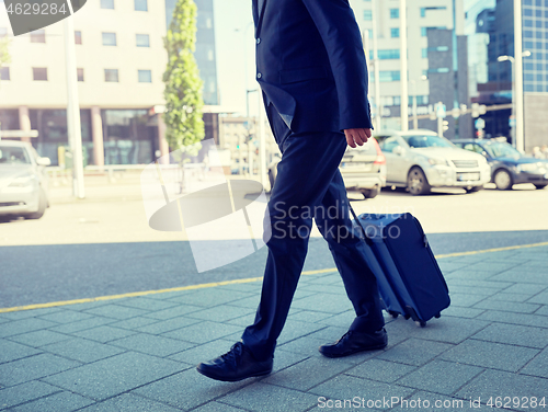 Image of senior businessman walking with travel bag in city