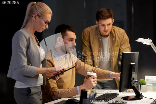 Image of business team with computer working late at office