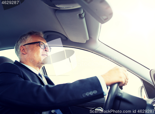 Image of happy senior businessman driving car