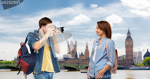 Image of happy couple of tourists with backpacks and camera