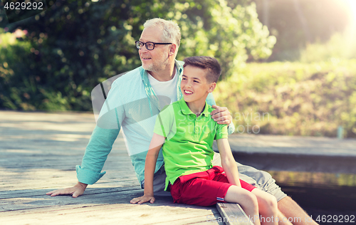 Image of grandfather and grandson sitting on river berth