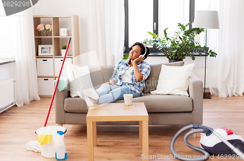 Image of woman in headphones resting after home cleaning