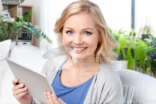 Image of middle aged woman with tablet computer at home