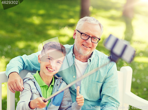 Image of old man and boy taking selfie by smartphone