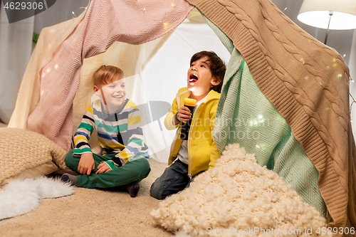 Image of happy boys with torch light in kids tent at home