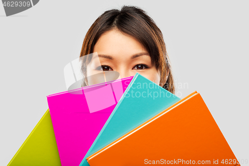 Image of asian woman or student hiding behind notebooks