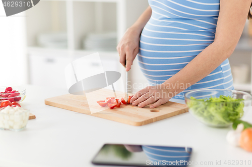 Image of close up of pregnant woman cooking food at home