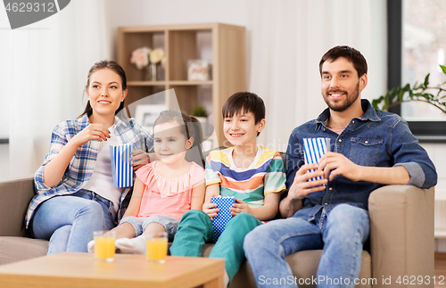 Image of happy family with popcorn watching tv at home