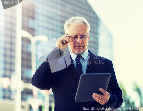 Image of senior businessman with tablet pc on city street