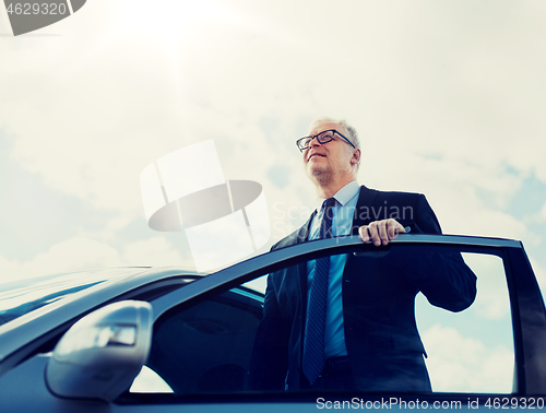 Image of senior businessman getting into car