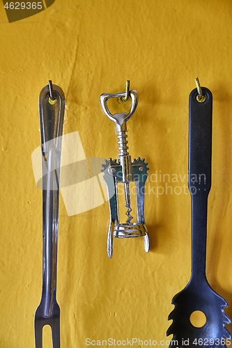 Image of Corkscrew and othe utensils on a kitchen wall