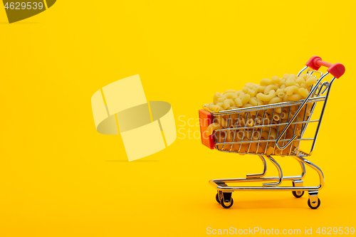 Image of Grocery trolley filled with pasta on a bright orange background
