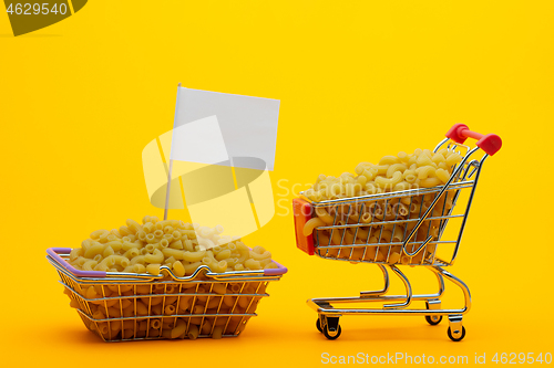 Image of The cart and the basket are filled with pasta on a bright orange background, a flag is stuck in the basket