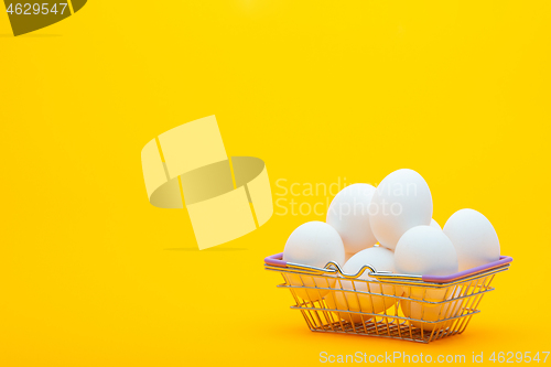 Image of Grocery basket with chicken eggs on an orange background