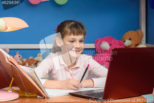 Image of Smiling girl at table at home studying at school.