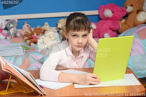 Image of The girl was forced to do homework and watch a boring video tutorial on a tablet