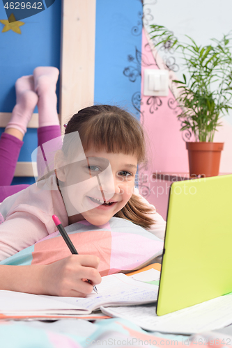 Image of Happy schoolgirl studying at home lying in bed