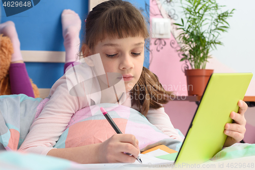 Image of Student in her bed at home studying at school online