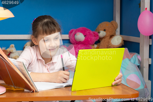 Image of A girl in a children\'s room sits at a table and studies online