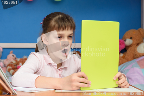 Image of Girl at home at the table yawns while watching a boring video tutorial