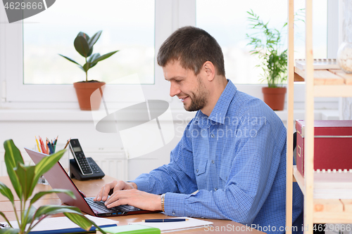 Image of Successful businessman works in the computer at the office