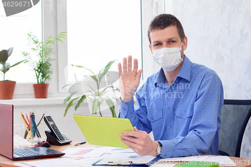 Image of Portrait of an office worker in a medical mask working remotely