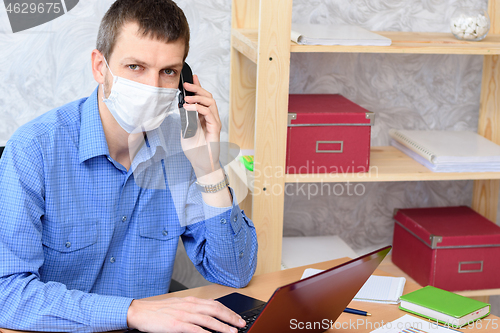 Image of Office specialist in a medical mask works at a computer in the office