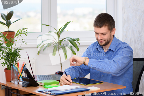 Image of A businessman looks at a watch while in the office at his workplace