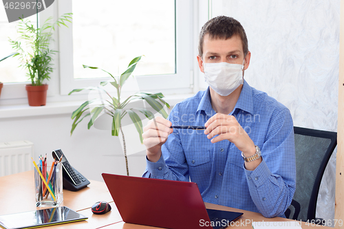 Image of Portrait of a businessman with a medical mask on his face in an office in quarantine