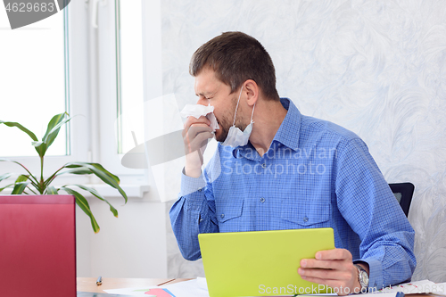 Image of A sick employee sneezes in an office and works remotely