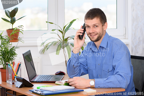 Image of Confident office specialist talking on the phone and looked into the frame