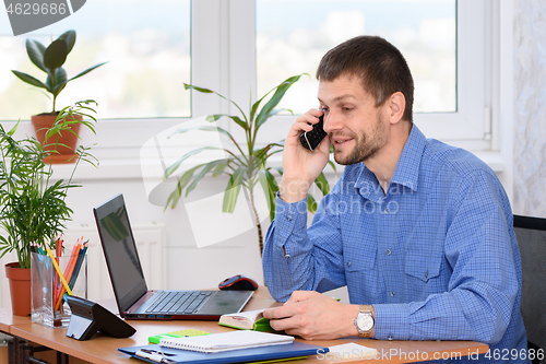 Image of A man in the office talking on the phone