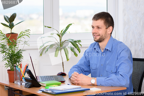 Image of The office employee at the workplace receives the client