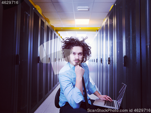 Image of engineer working on a laptop in server room