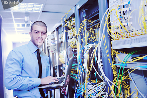 Image of businessman with laptop in network server room