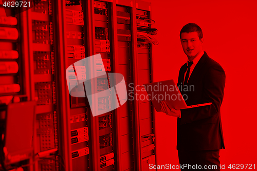 Image of businessman with laptop in network server room