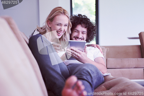 Image of couple relaxing at  home with tablet computers