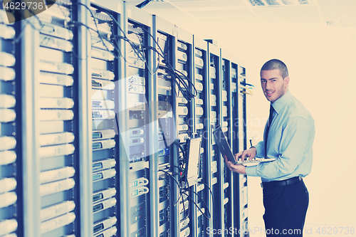 Image of businessman with laptop in network server room