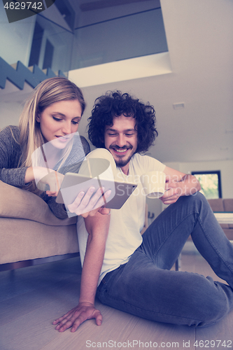 Image of couple relaxing at  home with tablet computers