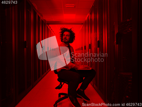 Image of engineer working on a laptop in server room