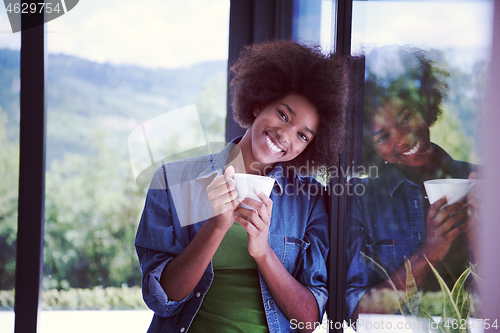 Image of African American woman drinking coffee looking out the window