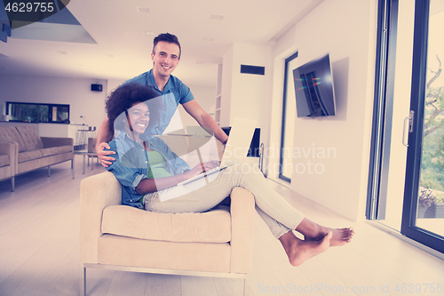 Image of multiethnic couple on an armchair with a laptop