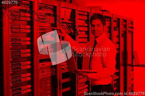 Image of businessman with laptop in network server room