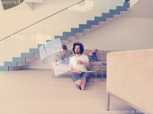 Image of couple relaxing at  home with tablet computers