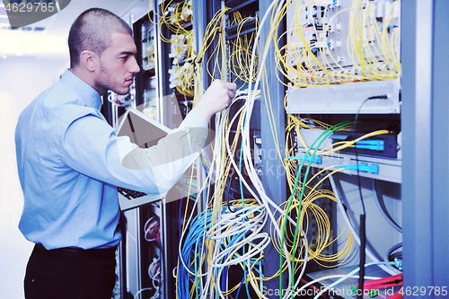 Image of businessman with laptop in network server room