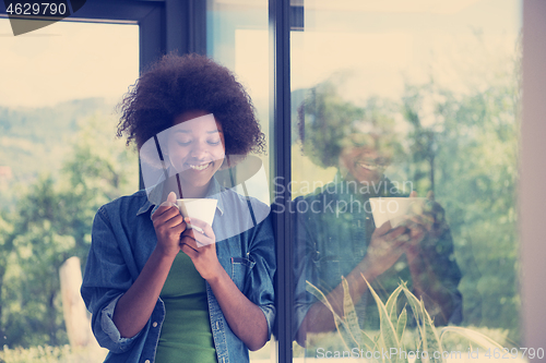 Image of African American woman drinking coffee looking out the window